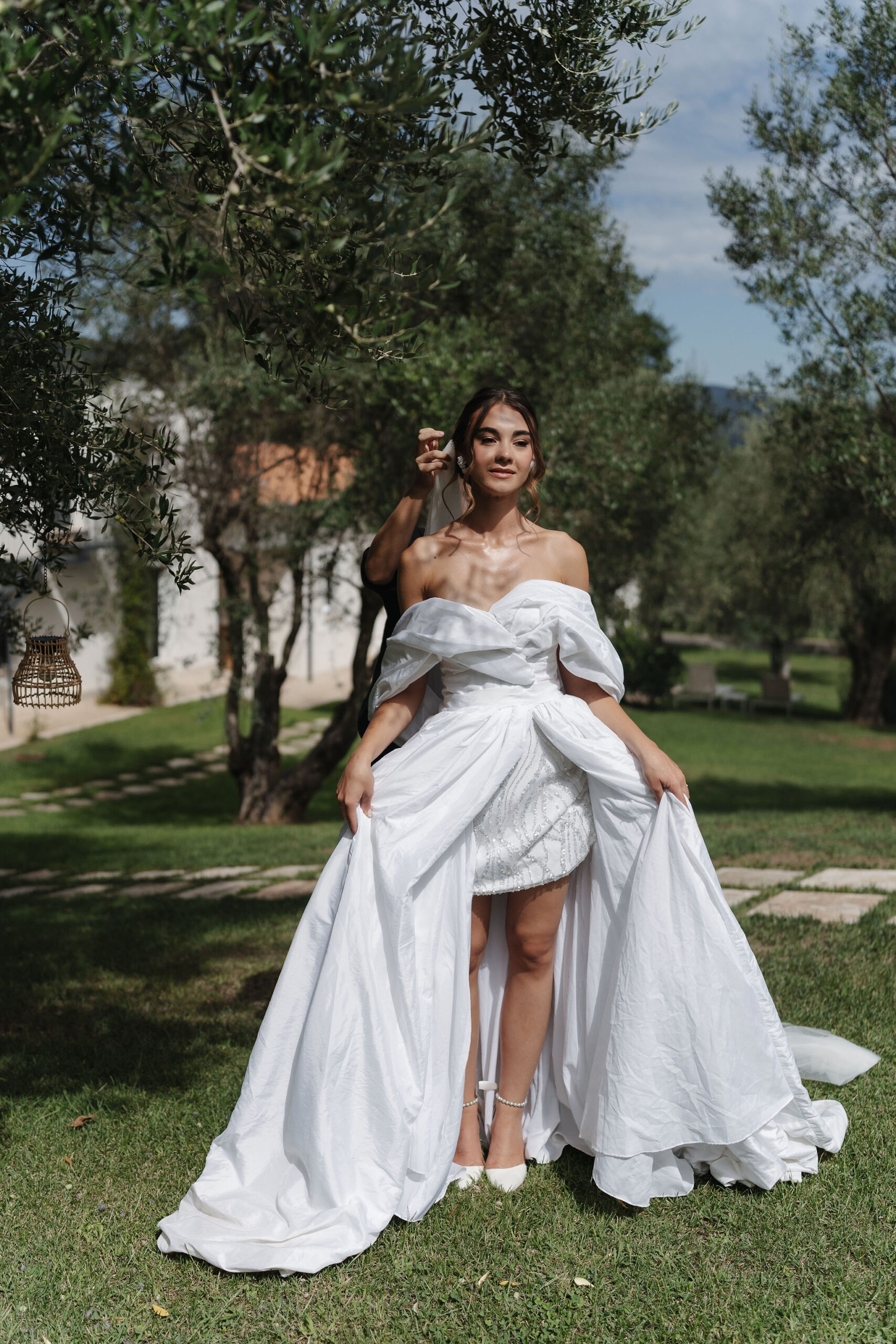 Braut im weißen schulterfreien Hochzeitskleid zwischen Olivenbäumen in der Vigna Caio