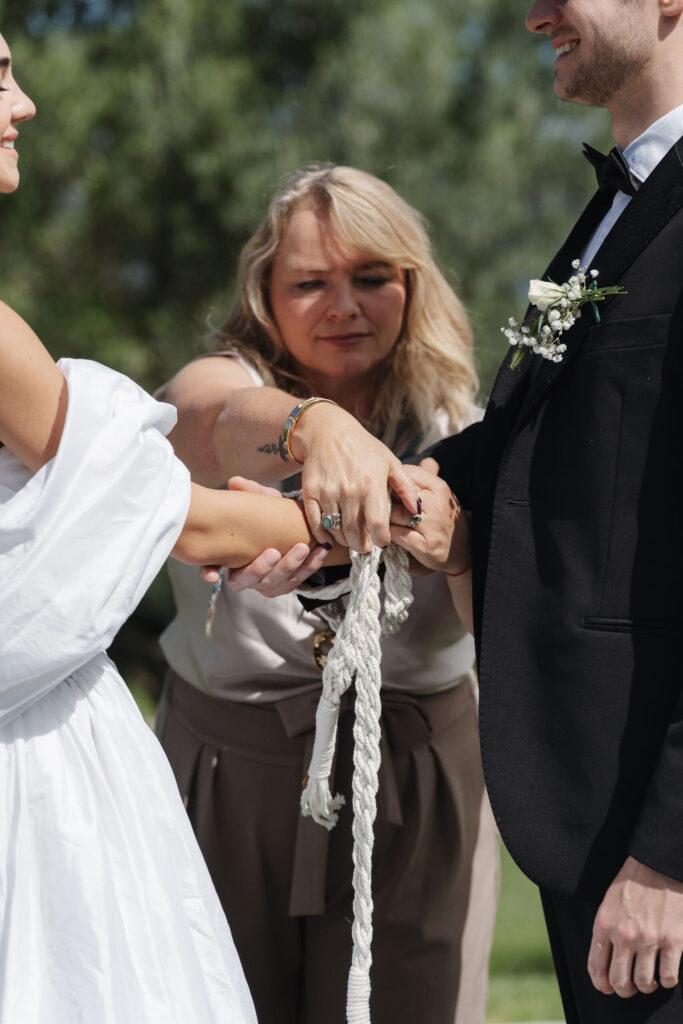 Traurednerin bindet die Hände des Brautpaars beim Handfasting in der Vigna Caio