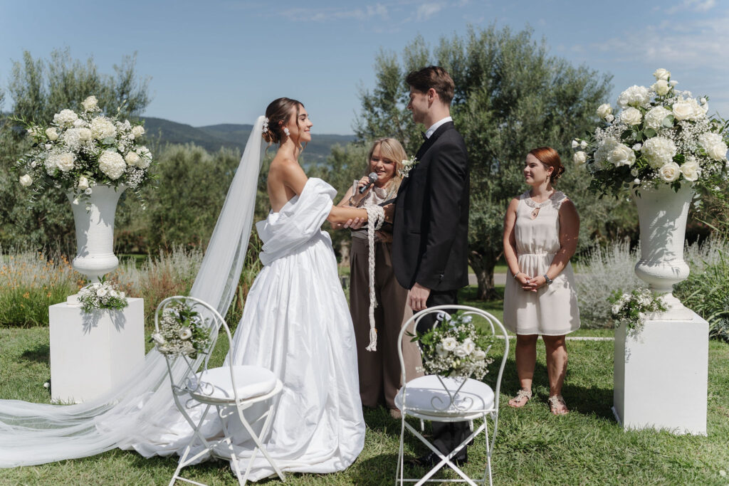 Handfasting bei der freien Trauung zwischen weißen Blumenarrangements in der Vigna Caio