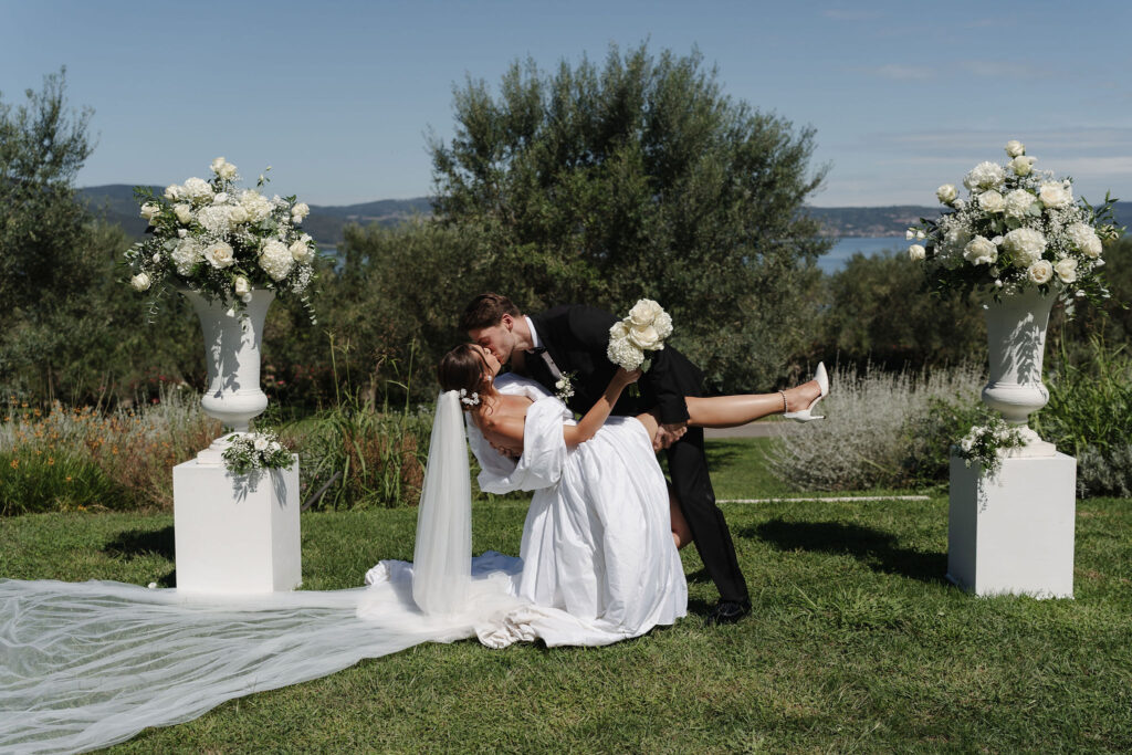 Brautpaar küsst sich zwischen weißen Blumenamphoren bei der Hochzeit in der Vigna Caio