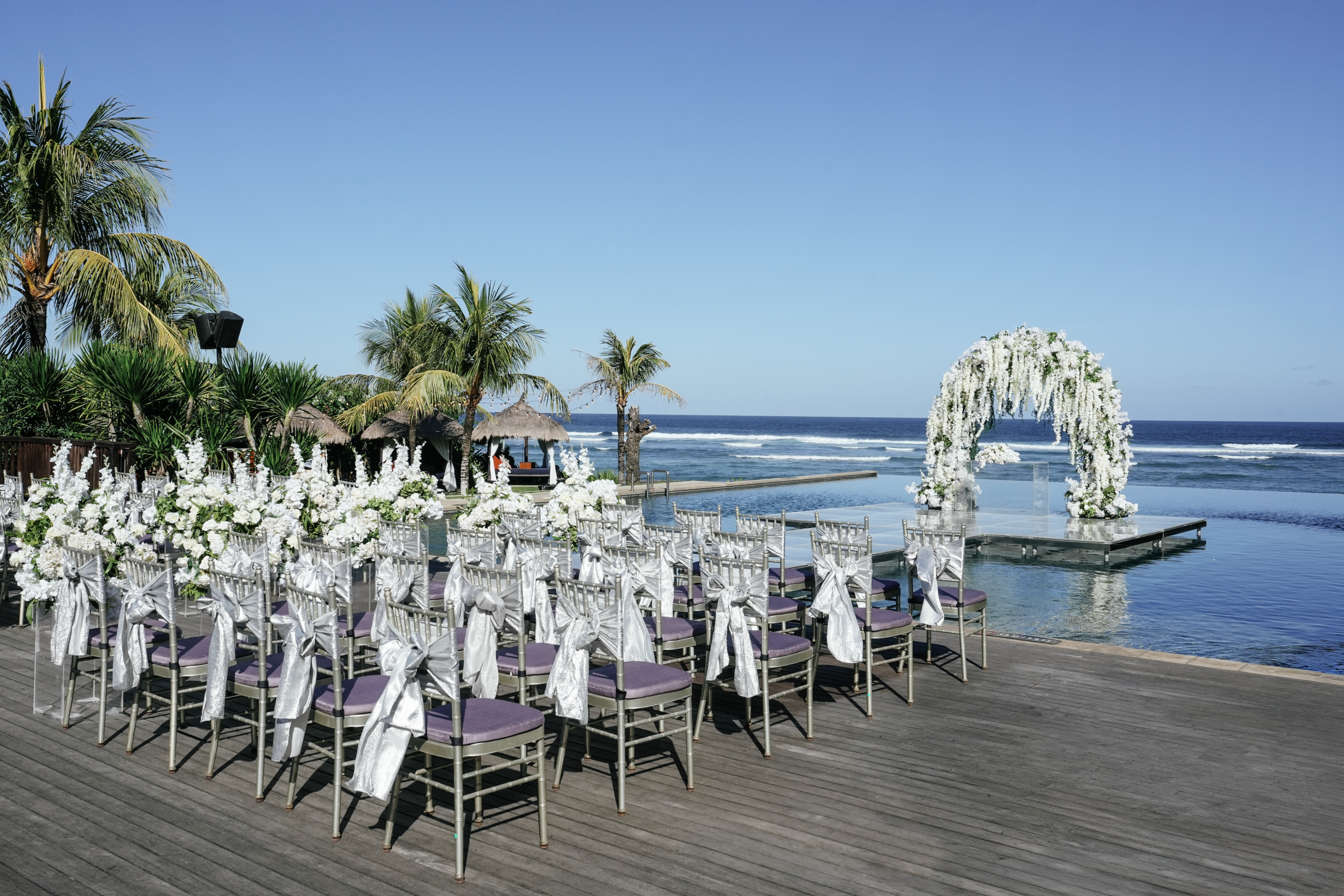 Weißer Blumenbogen am Meer unter Palmen für eine Hochzeit in Bali